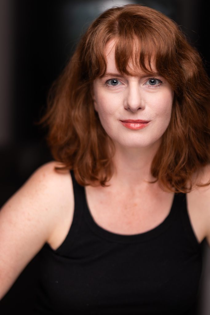 Elle is a beautiful young woman with long red hair.